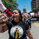 Protesters hold up signs as they march down Congress Ave at a protest outside the Texas state capitol on May 29, 2021 in Austin, Texas.